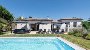 Une maison à deux étages dotée d’une piscine, d’un espace salon extérieur et d’un patio couvert.