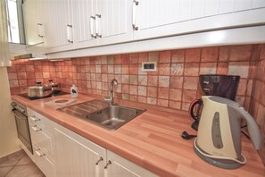 A kitchen with a stainless steel sink, a coffee maker, and a kettle on the countertop. - Tyche Two Bedroom Apartment (Pelekas)