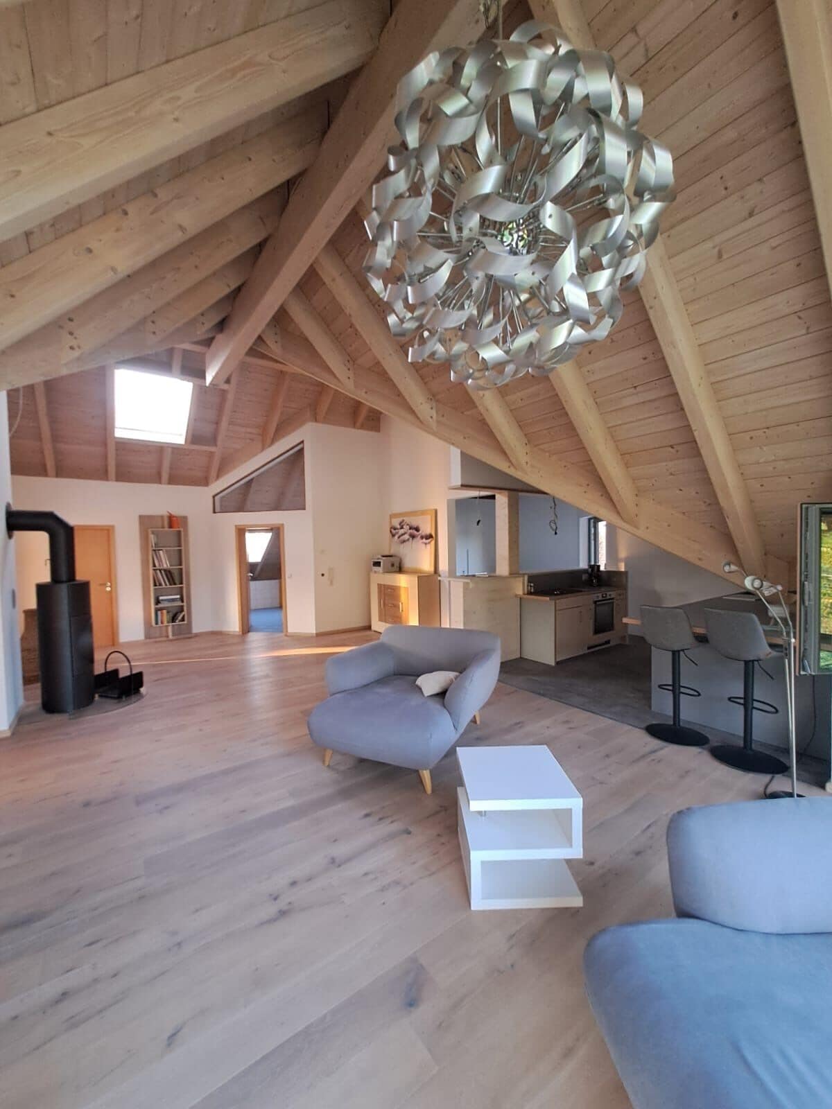 A spacious loft with high ceilings, a modern chandelier, and a cozy seating area.