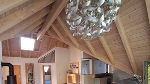 Un loft spacieux avec de hauts plafonds, un lustre moderne et un coin salon confortable.