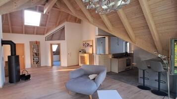 A spacious loft with high ceilings, a modern chandelier, and a cozy seating area.