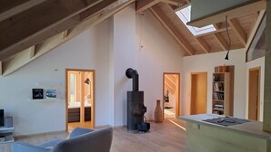 Un loft spacieux avec de hauts plafonds, des poutres apparentes, un poêle à bois intégré et un coin salon confortable.