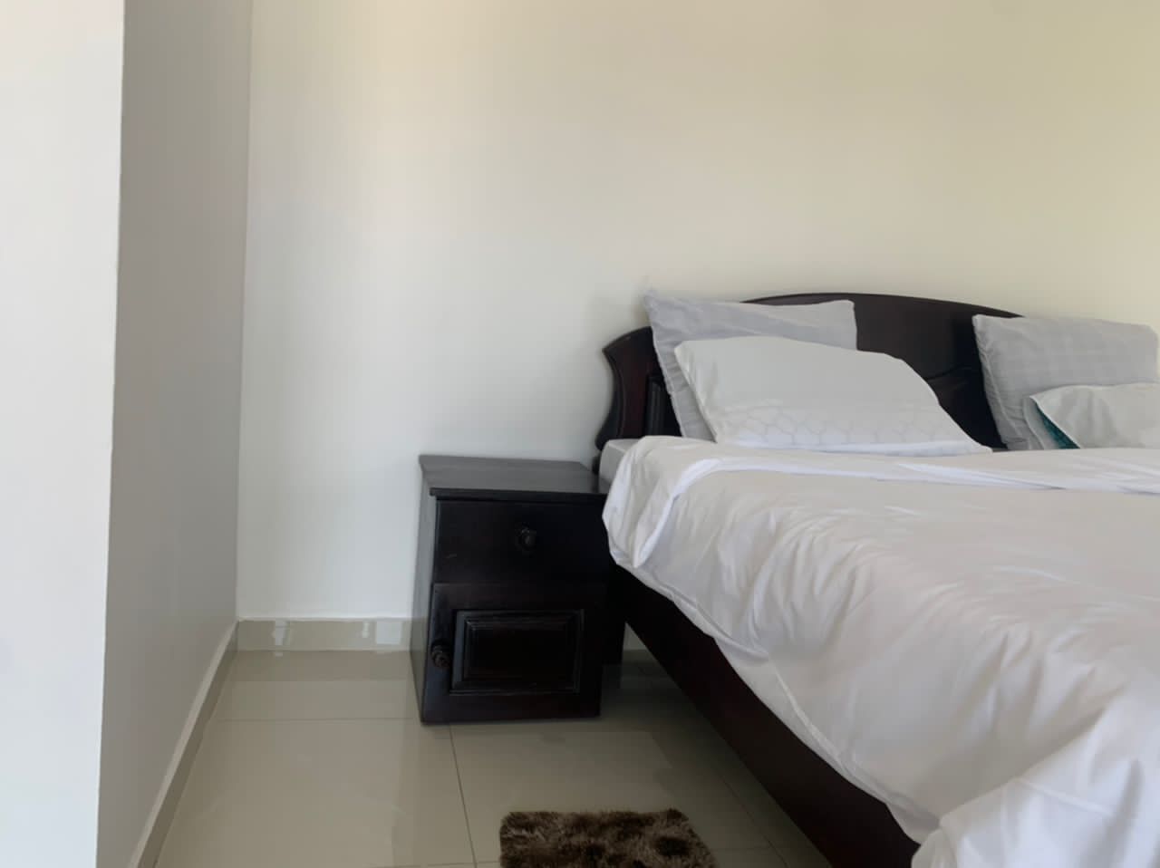 Een slaapkamer met een bed, een nachtkastje en een klein vloerkleed.