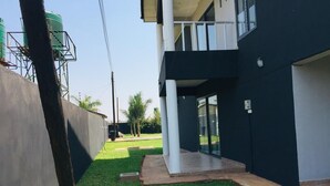Un edificio moderno con techo plano, balcón y patio cubierto de césped.