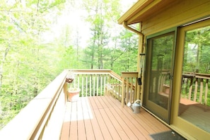 A wooden deck with a glass door, surrounded by a railing, overlooking a forested area. - Quail Cove 1617 at Rumbling Bald (Lake Lure)