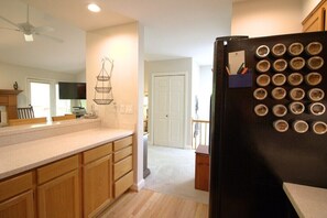 A kitchen with wooden cabinets, a black refrigerator with jars, and a ceiling fan. - Quail Cove 1617 at Rumbling Bald (Lake Lure)