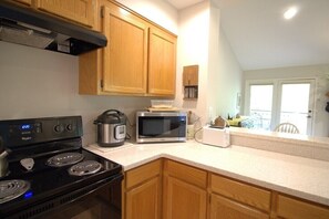 A kitchen with wooden cabinets, a stove, a microwave, and a toaster. - Quail Cove 1617 at Rumbling Bald (Lake Lure)