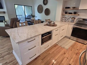 A modern kitchen with white cabinetry, a marble countertop, and a built-in oven. - Quail Cove 1631 at Rumbling Bald (Lake Lure)