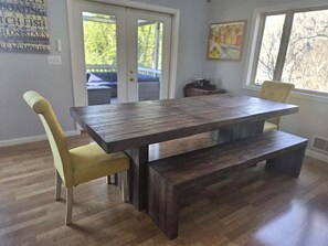 A dining area with a wooden table and two chairs, a bench, and a door leading outside. - Cloud 10 at Rumbling Bald (Lake Lure)