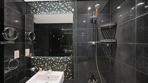 Un baño moderno con un espejo grande, un lavabo y una ducha.