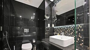 Un baño moderno con un espejo grande, un lavabo blanco y un inodoro.