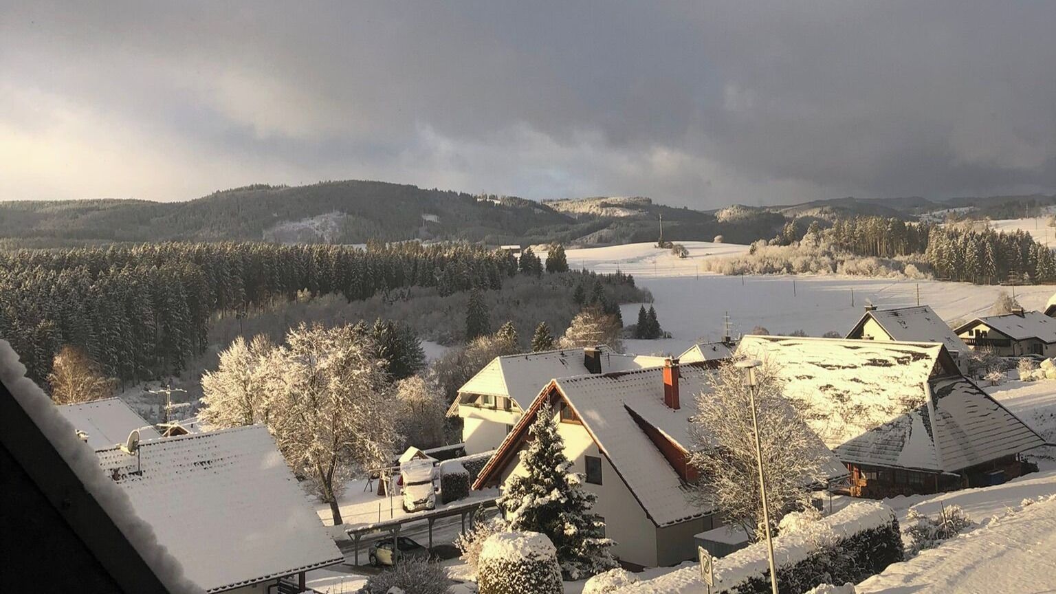 A snow-covered landscape with houses and a lake.