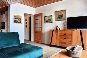 A living room with a teal sofa, wooden cabinet, and a television.