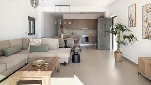 A modern living room with a sofa, coffee table, and dining area. - Elios Villas (Marathi)