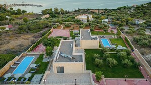 A resort with multiple swimming pools, a landscaped garden, and a view of the sea. - Elios Villas (Marathi)