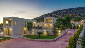 A modern two-story house with a stone facade, a paved driveway, and a landscaped garden with a small palm tree. - Elios Villas (Marathi)