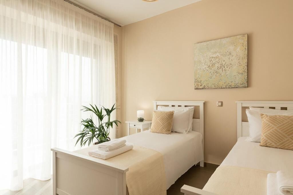 Une chambre d’hôtel avec deux lits, une table de chevet avec des serviettes, une plante et un tableau au mur.
