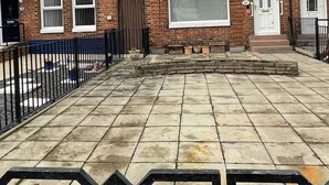 A brick terraced house with a tiled patio, a gated entrance, and a number '81' sign.