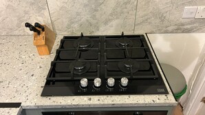 A kitchen with a four-burner stove, a knife block, and a COOKE & LEWIS brand oven.