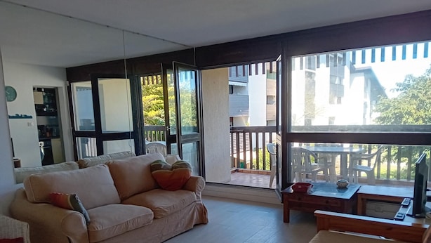 A living room with a sofa, a coffee table, and a view of the outside balcony. - Seignosse Penon - T2 Atlantic Coast Near Beach (Seignosse)