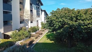 A modern multi-story residential building with balconies, a well-maintained garden, and a large tree in the foreground. - Seignosse Penon - T2 Atlantic Coast Near Beach (Seignosse)