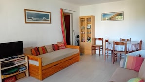A living room with a sofa, a TV, a cabinet, and a dining table with chairs. - Seignosse Penon - T2 Atlantic Coast Near Beach (Seignosse)
