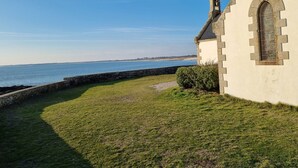 Un bâtiment situé sur la côte, doté d’un mur en pierre et d’une pelouse verdoyante.