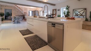 Una cocina moderna con una isla central, lavavajillas de acero inoxidable y una lámpara colgante.