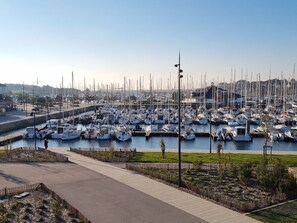 Een jachthaven met tal van boten, netjes gepositioneerd, omringd door een verhard pad en groen.