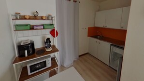 A compact kitchen with white cabinets, a microwave, a kettle, and a coffee maker on a wooden countertop.