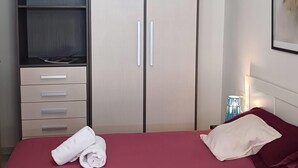Ein Hotelzimmer mit Bett, Kleiderschrank, Schreibtisch und Nachttisch.