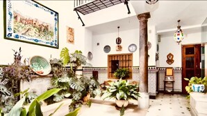 Ein großzügiger Innenbereich mit Fliesenboden, einer Säule und verschiedenen Kübelpflanzen.