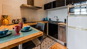 Cozinha moderna com mesa de madeira, forno embutido e coifa de aço inoxidável.