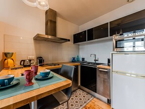 A modern kitchen with a wooden table, a built-in oven, and a stainless steel range hood. - Arcachon Center: T2 20m from Beach with Parking (Arcachon)