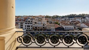 Varanda com grades de ferro forjado com vista para uma área urbana densamente povoada, com diversos edifícios e céu claro.
