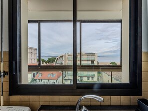 A bathroom with a window overlooking a cityscape and water. - Spacious T3 apartment with parking, balconies, 20m from Arcachon beach (Arcachon)