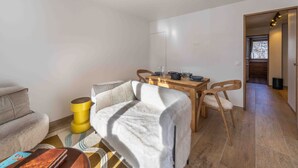 Ett mysigt vardagsrum med en soffa, ett soffbord och en matplats med ett bord och stolar.