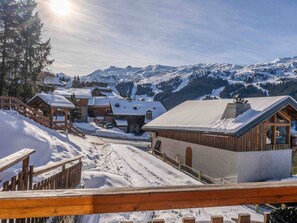 A snow-covered mountain village with wooden buildings, a wooden fence, and a clear view of the surrounding mountains. - Charming property in Méribel (Méribel)