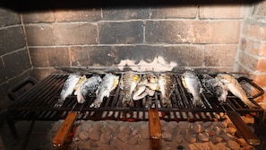 A grill with fish being cooked over charcoal. - Art House in Rovinj, Croatia - Vacation Home   (Rovinjsko Selo)