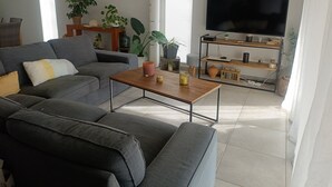 En moderne stue med en grå sofa, et træ sofabord og et fladskærms-tv på et træstel.
