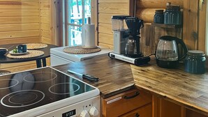 Una cocina con paredes de madera, estufa, cafetera y un reloj.