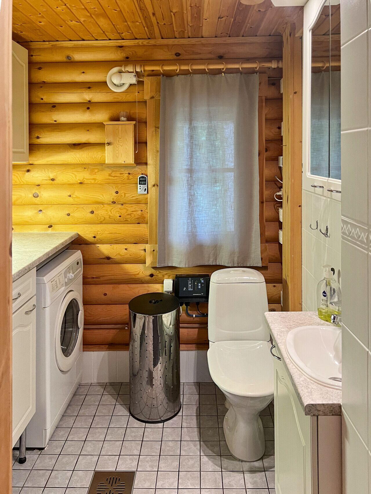 Un baño de cabaña de madera compacto con lavadora, inodoro y lavamanos.