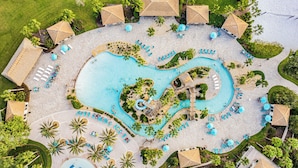 An aerial view of a resort with a central swimming pool, sun loungers, and palm trees. - Oasis at Champions Gate: Pool, Spa & Arcade Fun! (Davenport)