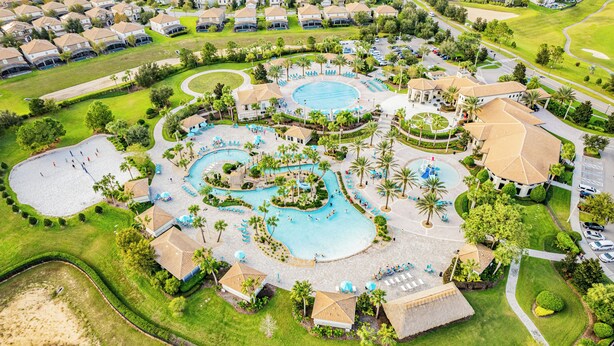 An aerial view of a resort with multiple swimming pools, palm trees, and a golf course. - Oasis at Champions Gate: Pool, Spa & Arcade Fun! (Davenport)