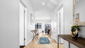 A modern hallway with white walls, a wooden floor, and a blue patterned rug. - Oasis at Champions Gate: Pool, Spa & Arcade Fun! (Davenport)