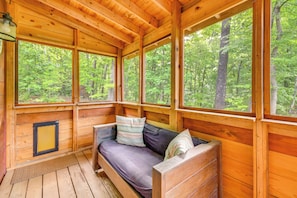 A wooden cabin with a built-in sofa, large windows, and a view of a forest. - Hike & Bike! Peaceful Wooded Retreat in Old Fort (Old Fort)