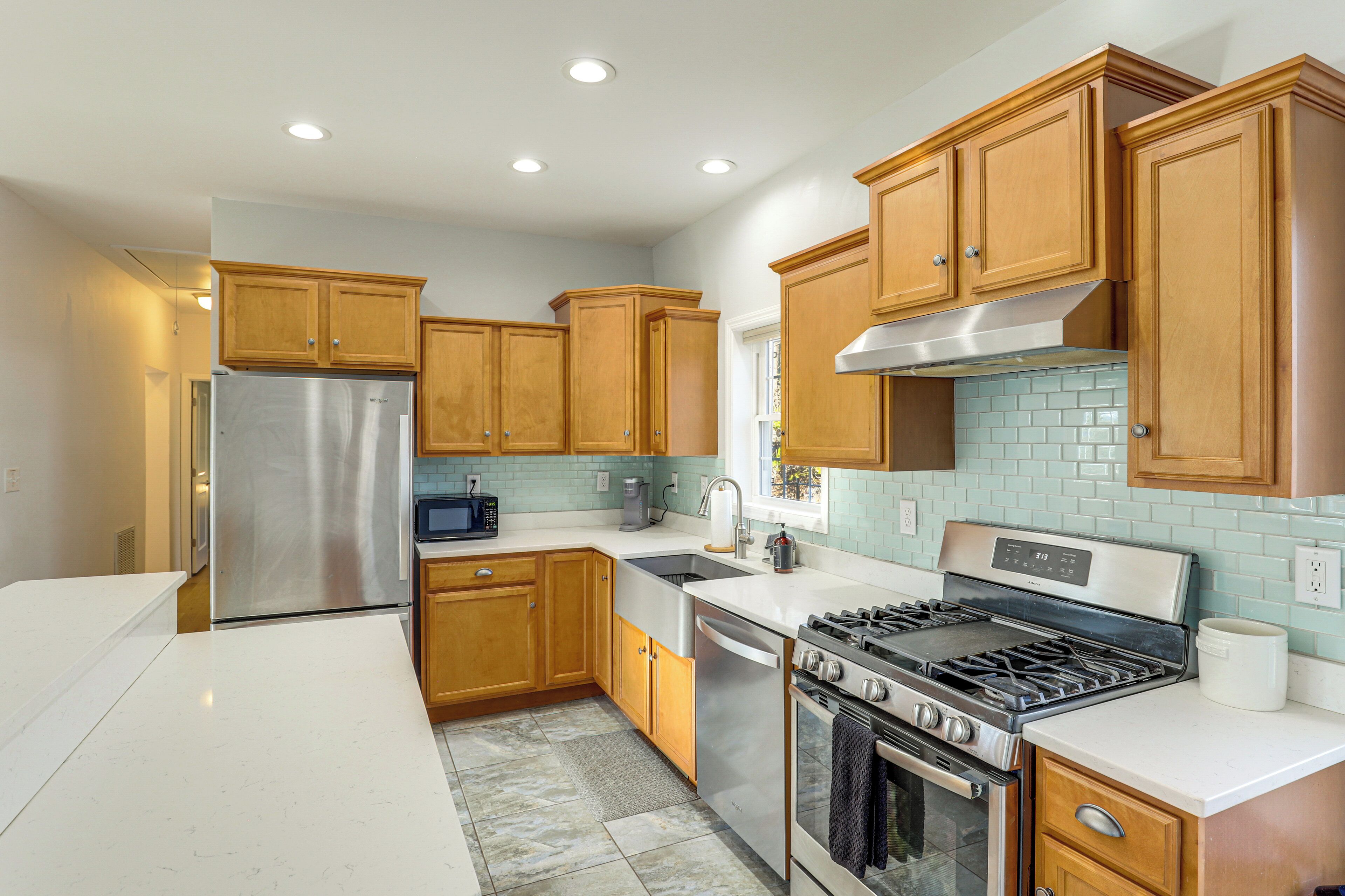 A modern kitchen with wooden cabinets, stainless steel appliances, and a tiled backsplash.
