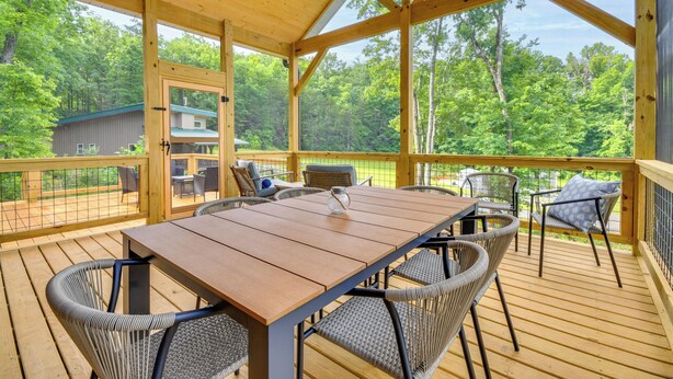 A wooden deck with a table and chairs, surrounded by a wooden railing, overlooking a forested area. - Hike & Bike! Peaceful Wooded Retreat in Old Fort (Old Fort)