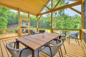 A wooden deck with a table and chairs, surrounded by a wooden railing, overlooking a forested area. - Hike & Bike! Peaceful Wooded Retreat in Old Fort (Old Fort)