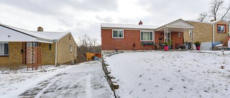 Ett bostadsområde med hus byggda av tegel, en snötäckt uppfart och en liten trädgård.